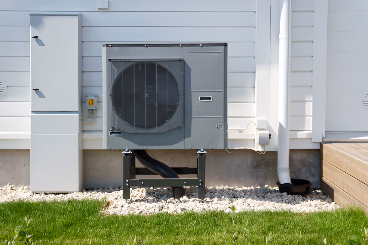 Ground-mounted air conditioning unit beside a white house, efficiently cooling the home.